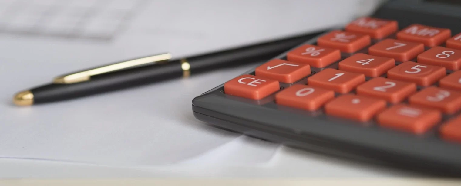 Calculadora e caneta em uma mesa com papéis